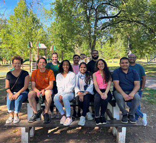 A group of people sitting on a bench  Description automatically generated with medium confidence